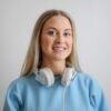 Portrait of a happy woman with headphones, wearing a blue top, smiling warmly.