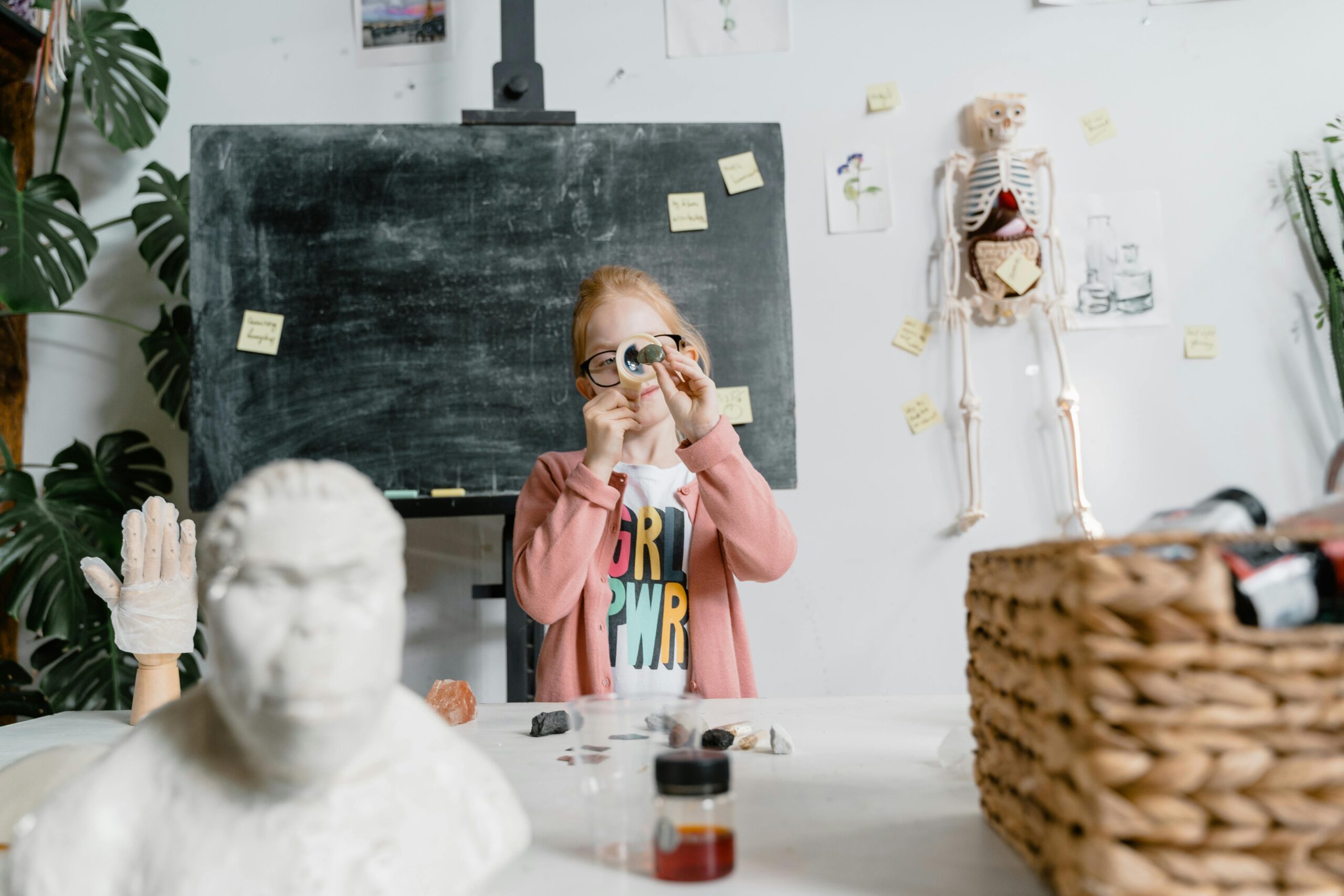 Young girl enthusiastically explores science in a classroom setting with a magnifier.